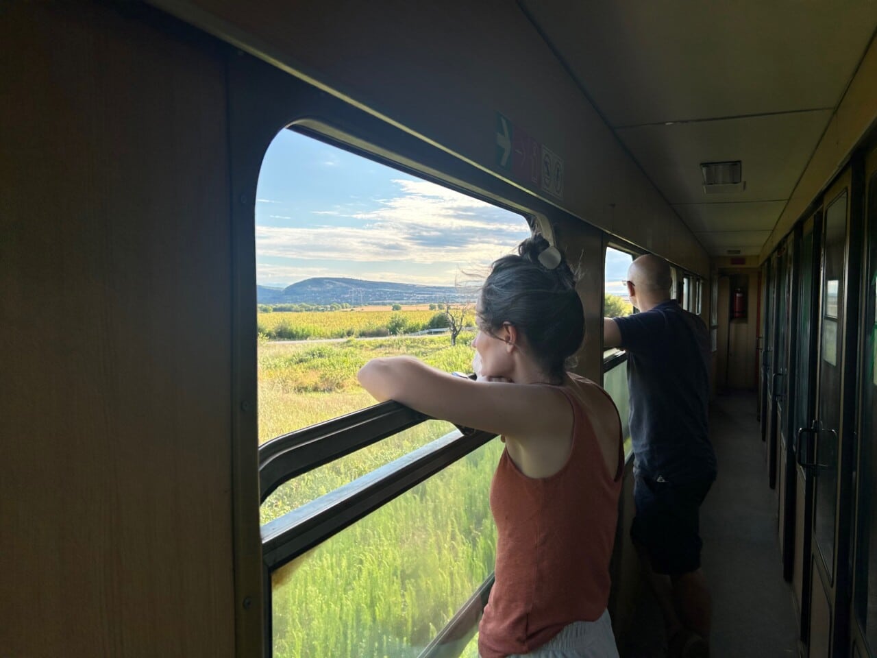 Foto einer Frau, die am offenen Fenster eines Zuges steht. 